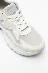 Zapatillas deportivas color gris claro con recortes en gamuza y textil transpirable, cordones a tono y plataforma de 5cm de alto.