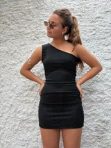 Vestido corto negro de lurex, con un solo hombro y corte ajustado al cuerpo.