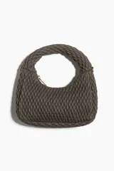 Cartera bandolera color gris topo, con asa corta superior trenzada y correa larga extraíble. Diseño guateado con cierre superior.