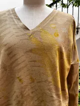 Remera de manga larga color beige con estampado botánico verde y amarillo, escote en V, corte ajustado y tajos laterales.