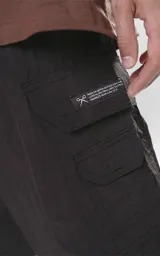 Bermuda cargo negra de nylon y spandex, con calce relax-fit, cintura elástica, cordón de ajuste y bolsillos delanteros con fuelle.