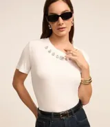 Blusa blanca de mangas cortas confeccionada en viscosa, con cuello redondo adornado con brillos florales.