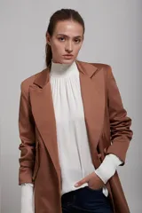 Saco blazer color beige, de corte clásico con solapas y cierre frontal con botones.