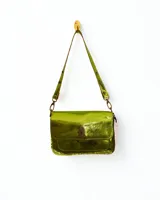 Cartera bandolera de cuero con correa regulable y cierre metálico frontal. Diseño compacto, práctico y moderno, con efecto iridiscente en tonos verdes, dorados y azules.