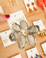 Aretes colgantes plateados con diseño floral tridimensional, compuesto por cinco pétalos metálicos con textura martillada y acabado brillante.