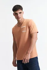 Remera color durazno de manga corta con cuello redondo y estampado frontal con texto en recuadro.