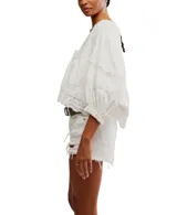 Blusa blanca de algodón con escote en V, mangas globo 3/4 con detalles de encaje y puños elásticos. Presenta lazos en el frente para atar.