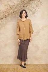 Camisa blanca de lino con cuello mao, mangas 3/4 con botón para sujetar, cierre con botones a tono y ajuste con cordón en la cintura.