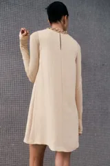 Vestido corto sin mangas color beige. Modelo levemente evasé con escote redondo, abertura de cerradura con botón oculto en la nuca y bajo recto. Parcialmente forrado.