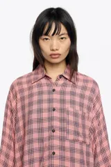 Camisa blanca de corte ancho y silueta relajada, con cuello camisero, botones frontales, manga 3/4 ancha con puño y bolsillo de plastrón en el pecho.