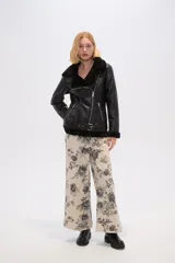 Chaqueta negra de cuero sintético con interior de piel sintética, corte al cuerpo, cierre frontal asimétrico con cremallera, cuello solapa con hebillas y cinturón con hebilla en la cintura.