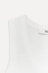 Musculosa blanca de algodón con cuello redondo y sisas anchas.