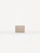 Billetera pequeña color visón, con solapa y cierre a presión. Diseño acolchado con pespuntes en forma de V y logo metálico con forma de labios.