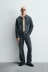 Pantalón de jean de tiro medio, color gris oscuro con efecto lavado, corte ajustado en la parte superior y acampanado desde la rodilla, con cinco bolsillos y cierre frontal con cremallera y botón.