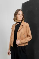 Chaqueta color beige de tela tipo gamuza con elastano, cuello solapa, manga larga con trabillas en hombro, bolsillos delanteros con cremallera metálica y cierre frontal con cremallera.