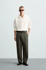 Pantalón verde oliva de corte amplio con pliegues en la parte delantera, bolsillos laterales y traseros de ojal.