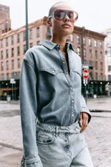 Camisa de denim celeste, de corte recto, con cuello solapa, manga larga, dos bolsillos frontales con solapa y cierre frontal con botones.