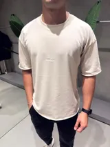 Remera de algodón pesado color beige, con cuello redondo y mangas cortas. Presenta un pequeño logo bordado en el pecho.