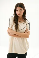 Remera negra de corte holgado con cuello redondo y mangas cortas con dobladillo. Presenta una línea diagonal blanca que cruza el frente desde el hombro hasta la cadera.
