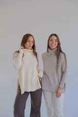 Sweater color crema de corte recto con cuello alto y aberturas laterales.