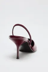 Zapato destalonado acharolado color borgoña, con escote en pico, cierre con tira trasera ajustable, tacón fino y punta fina.