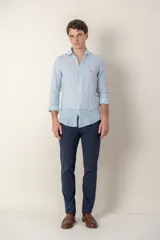 Pantalón de vestir color gris claro, de corte slim fit, con bolsillos laterales y traseros. Se ajusta a la cintura con cinturón de cuero marrón.