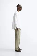 Camisa color beige claro, de corte relaxed fit, confeccionada en tejido de lino y algodón. Tiene cuello mao, manga larga con puños abotonados y cierre frontal con botones.