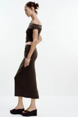 Falda midi color crema, de tiro alto con cintura elástica y detalle de pliegues laterales.