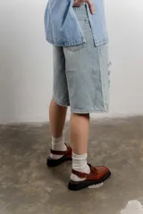 Zueco negro con textura croco, diseño tipo mocasín y tira regulable al talón.