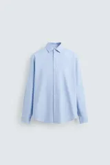 Camisa celeste de corte slim fit, confeccionada en tejido de algodón. Tiene cuello italiano, mangas largas con puños abotonados y cierre frontal con botones.