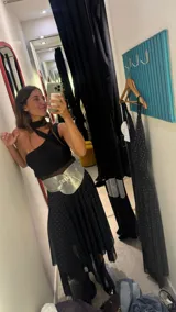 Vestido midi negro con estampado de lunares blancos, breteles finos y falda con volados y transparencias.