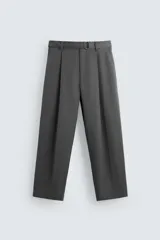 Pantalón negro de corte amplio con cinturón de tela con hebilla metálica. Presenta pliegues frontales, bolsillos laterales y traseros. Cierre frontal con cremallera y botón.