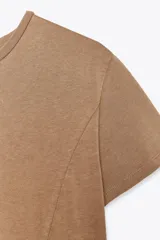 Vestido largo color marrón claro, de corte recto, con cuello redondo, mangas cortas y bajo asimétrico con volados.