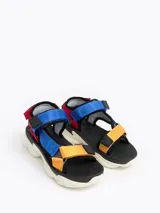 Sandalias con plataforma blanca y tiras de velcro ajustables en colores rojo, azul y amarillo.
