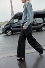 Jeans de denim oscuro, tiro alto, corte pierna ancha (wide leg) y cinco bolsillos. Presenta costuras contrastantes en color claro.