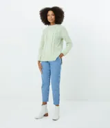 Suéter blanco de punto trenzado con cuello redondo y mangas largas.