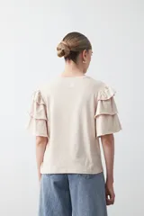 Remera negra de algodón con cuello redondo y mangas cortas con volados en capas.