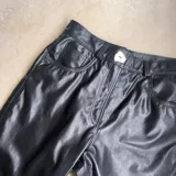Pantalón de cuero negro, de corte recto y tiro alto, con bolsillos delanteros y traseros.