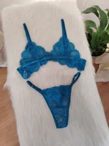 Conjunto de lencería de dos piezas (corpiño y bombacha tipo colaless/tanga) de encaje floral, color verde petróleo/turquesa oscuro. El corpiño es triangular con tirantes ajustables y la bombacha es de corte bajo con bordes festoneados.