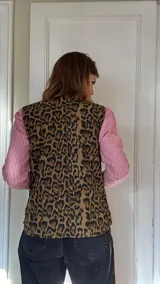 Chaleco reversible con un lado de corderito negro y otro de tussor con estampado animal print.