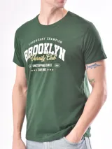 Remera verde con estampa frontal con la inscripción "Brooklyn Varsity Club" en color blanco y detalles en amarillo.
