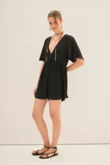 Vestido corto negro con escote en V y efecto foil. Presenta mangas amplias tipo mariposa y un corte holgado con frunce bajo el busto.