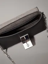 Cartera cruzada negra de piel sintética granulada, con correa de cadena plateada y cierre de solapa con placa metálica con el logo de Calvin Klein grabado.