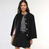 Chaleco tipo capa color negro con cuello redondo y cierre frontal con botones dorados.