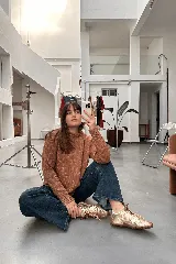 Sweater color ladrillo con hilos metalizados, cuello redondo y corte relajado con aberturas laterales y terminaciones acanaladas.