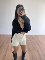 Short blanco de bengalina elastizada con cordones cruzados en la parte delantera y flecos en los laterales.