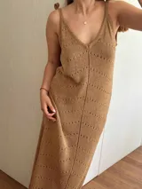 Vestido largo color dorado tejido con hilo de algodón y lurex, con escote en V, tirantes finos regulables y espalda descubierta. Presenta tajos laterales.