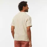 Camisa de manga corta color crema con rayas verticales marrones, cuello cubano y cierre frontal con botones.