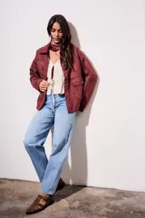 Sobrecamisa color borgoña de gamuza sintética con cuello camisero, cierre frontal con botones a tono, bolsillos de parche con solapa en el pecho y mangas largas con puños abotonados.