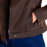 Chaqueta marrón de corte entallado, con cuello mao y cierre frontal con cremallera. Cuenta con bolsillos laterales con cremallera, puños con cremallera y etiqueta de cuero sintético con el logo de Caterpillar en el pecho.